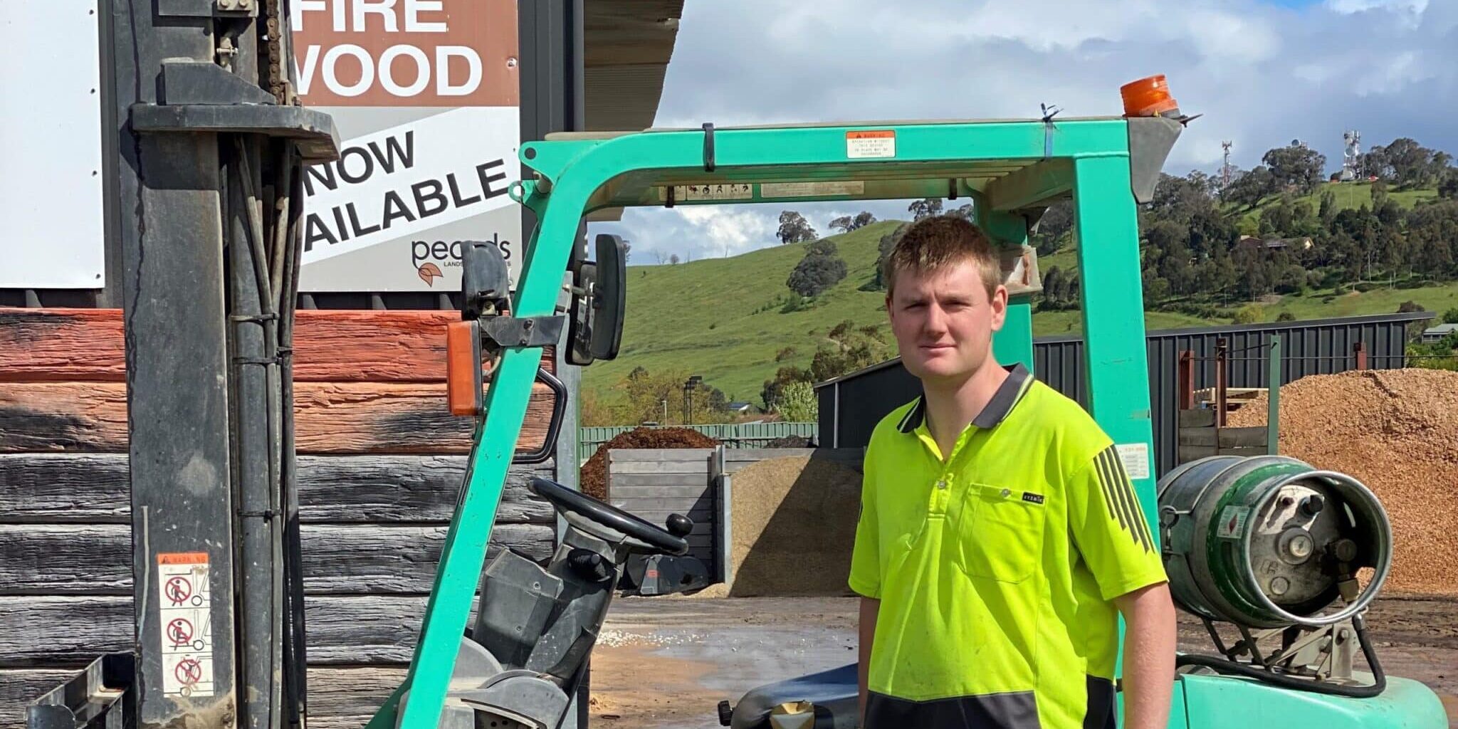 Nicholas standing next to forklift at worksite