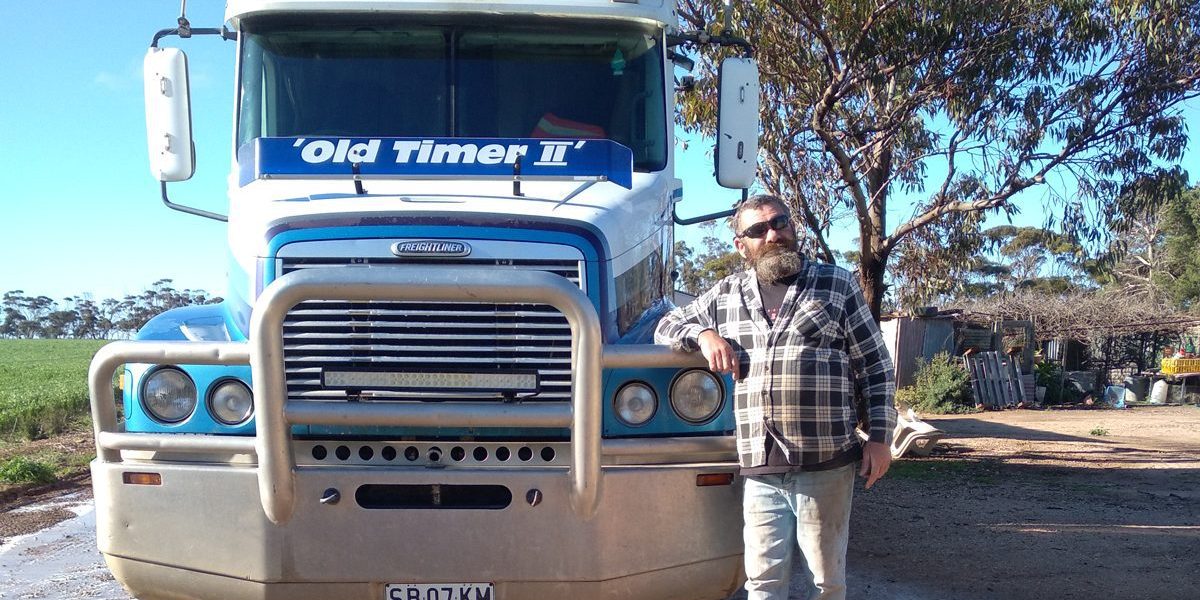 Mark stands in front of his truck in the work yard