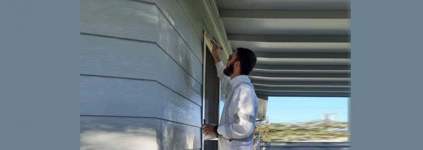 Reece at work painting a grey residential house